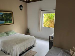 ein weißes Schlafzimmer mit einem Bett und einem Fenster in der Unterkunft Lumiar Garden Suítes e Chalés em Vilas do Atlântico in Lauro de Freitas