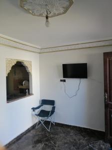 a room with a chair and a television on a wall at Dar Sofiane in Sidi Bouzid