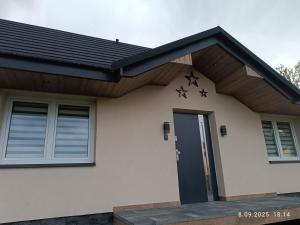 a house with a black door and a wooden roof at Apartament Pod Gwiazdami in Czarny Dunajec