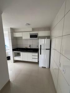 una cucina con mobili bianchi e un frigorifero bianco di Ape 2 quartos a Guarujá