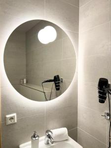 a bathroom with a round mirror and a sink at Lonid Apartment in Höfn +14 photos