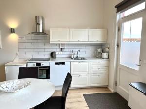 a kitchen with white cabinets and a table and a sink at Lonid Apartment in Höfn
