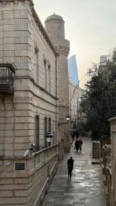 a man walking down a street next to a building at Old city apart in Baku