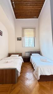 two beds in a room with white walls and wooden floors at Old city apart in Baku
