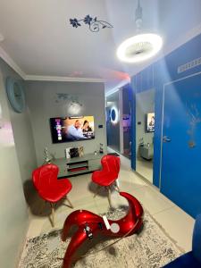 a living room with red chairs and a tv at Flowsort Grand Apartments 2 in Durban