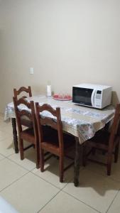 a table with chairs and a microwave on top of it at Apê perto do Parque Euclides Dourado in Garanhuns