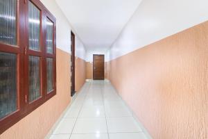 an empty hallway with windows and a white tile floor at Hotel O Aluva Railway Station Formerly Menachery Tourist Home in Alwaye