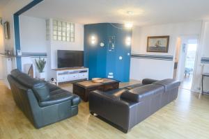 ein Wohnzimmer mit 2 Ledersofas und einem TV in der Unterkunft Le Trez', vue mer imprenable in Plougonvelin