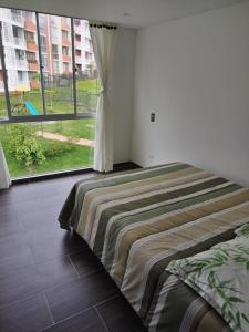 una cama en una habitación con una ventana grande en Tranquilan-dias, en Guaduas