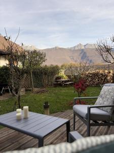 une table et des chaises sur une terrasse avec des montagnes en arrière-plan dans l'établissement Venez Chez Vous Parenthese du lac, à Lathuile