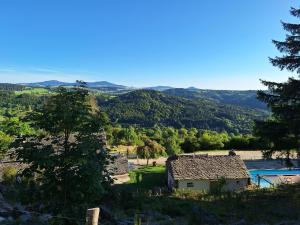 a small house in a field with mountains in the background at Auberge & Camping Sabatoux in Montusclat
