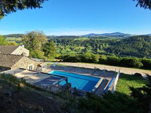 Una vista aérea de una piscina frente a una casa. en Auberge & Camping Sabatoux, en Montusclat