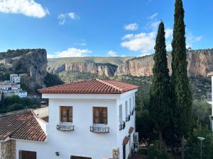 une maison blanche avec des montagnes en arrière-plan dans l'établissement Apartamentos La Muela - Chulilla, à Chulilla