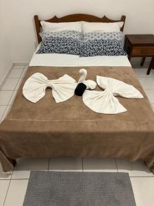 a bed with two towels and a bow tie on it at Pousada Casarão - Pé na Areia Cumuruxatiba in Cumuruxatiba