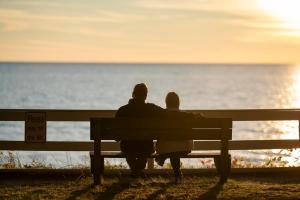Ein Paar, das auf einer Bank sitzt und den Ozean ansieht in der Unterkunft Scenic Drive Resort in Muskegon