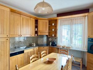 een keuken met houten kasten en een tafel met stoelen bij Ca' Prestin - Natura e Relax a 20 minuti da Bormio in Tovo di Sant'Agata