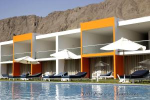a building with chairs and umbrellas next to a pool at Hotel Vallehermoso Lunahuana in Lunahuaná