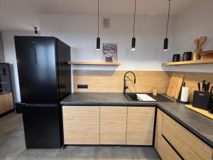 a kitchen with a black refrigerator and wooden cabinets at Loft Re Design Apartament in Głogów