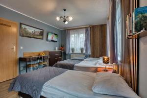 um quarto de hotel com duas camas e uma escrivaninha em Zajazd Karłów Restauracja & Pokoje Gościnne em Karłów