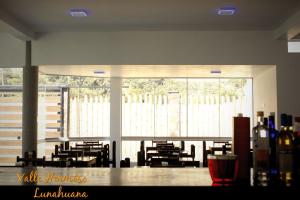 a dining room with tables and chairs and large windows at Hotel Vallehermoso Lunahuana in Lunahuaná
