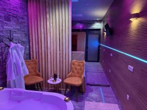 a bathroom with a tub and two chairs and a table at Dubai Spa Apartments in Novi Sad