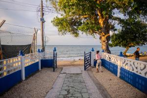 a woman sitting on a fence near the beach at Casa Claro del Mar in Coveñas