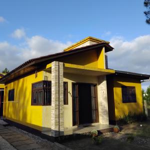 ein gelb-weißes Haus mit einer Veranda in der Unterkunft A Casa Amarela - Morada dos Maçaricos - Tranquilidade próxima ao mar in Balneário Gaivotas