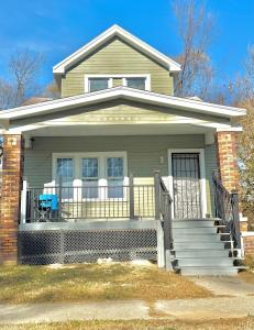 底特律Alma garden inn的一栋带有前廊的房子，门廊上放着一把蓝色的椅子