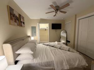 une chambre avec un lit avec des draps blancs et un ventilateur de plafond dans l'établissement Luxe Getaway by AT&T & Six Flags, à Grand Prairie