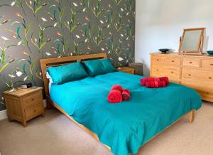 two red stuffed animals sitting on a blue bed at Spacious Edwardian home in Stroud