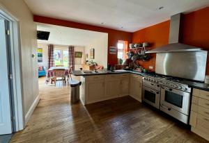 a kitchen with orange walls and a stove top oven at Spacious Edwardian home in Stroud