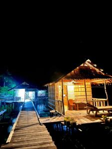 a wooden dock with a hut at night at Homestay Yenbeyar Raja Ampat in Yariffi