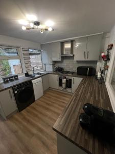 a kitchen with white cabinets and a wooden floor at Entire luxury home in Manchester in Bury