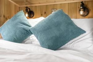 two green pillows sitting on a white bed at Starry Nights Escape - Hot Tub & Sauna in Yarpole