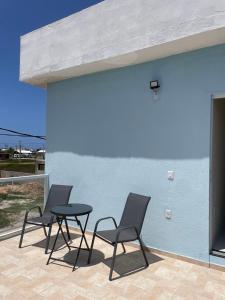 three chairs and a table in front of a blue wall at Ventos de Arubinha in Arraial do Cabo