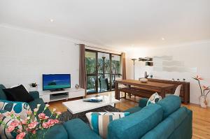 ein Wohnzimmer mit einer blauen Couch und einem Fernseher in der Unterkunft Somerset Sunrise Townhouse in Byron Centre in Byron Bay