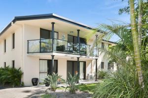 ein weißes Haus mit einem Balkon und Palmen in der Unterkunft Somerset Sunrise Townhouse in Byron Centre in Byron Bay