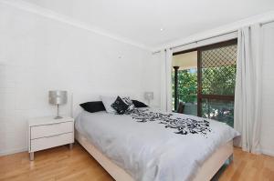 ein weißes Schlafzimmer mit einem Bett und einem Fenster in der Unterkunft Somerset Sunrise Townhouse in Byron Centre in Byron Bay