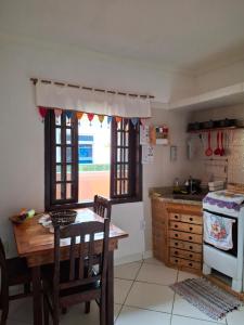 a kitchen with a wooden table and a stove and windows at Suite Baia dos Corais Praia de Provetá Ilha Grande in Angra dos Reis