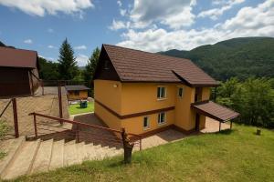 a small yellow house with a brown roof at Villa Bilugu in Valea de Brazi