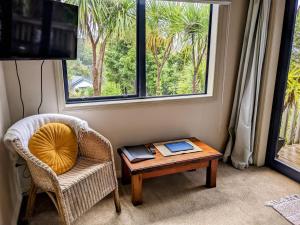 a room with a chair and a table and a window at Pilgrim's Rest in Whangarei