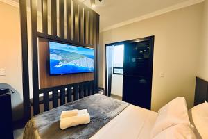 ein Schlafzimmer mit einem Bett und einem Fernseher an der Wand in der Unterkunft Loft 306 - Praticidade e estilo na esquina da Ufu in Uberlândia