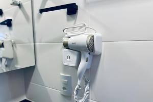 ein Haartrockner, der an einer Wand in einem Badezimmer hängt in der Unterkunft Loft 306 - Praticidade e estilo na esquina da Ufu in Uberlândia