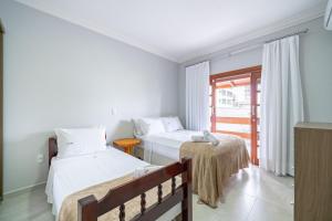 two beds in a room with a window at Achei Itapema • Casa, 4 suítes + Área Gourmet in Perequê