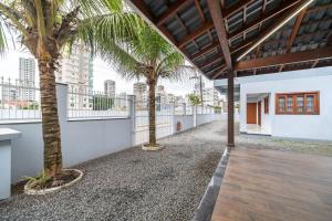 two palm trees on the balcony of a house at Achei Itapema • Casa, 4 suítes + Área Gourmet in Perequê