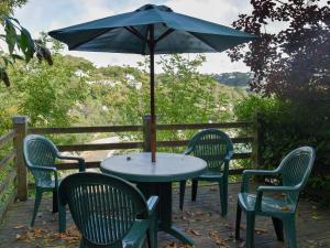 a table and chairs with an umbrella on a deck at Estuary House Flat 3 in Salcombe