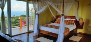 um quarto com cama de dossel e varanda em Kaye Mango em Soufrière