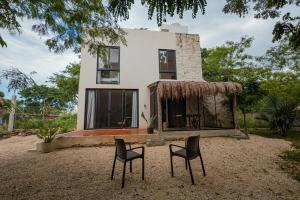 a house with two chairs in front of it at Your Refuge in the Mayan Jungle Cobá, 2 Bedrooms in Cobá