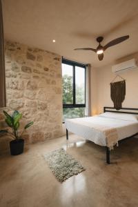 a bedroom with a bed and a stone wall at Your Refuge in the Mayan Jungle Cobá, 2 Bedrooms in Cobá