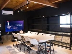 ein Konferenzraum mit Tisch und Stühlen und einer Leinwand in der Unterkunft Rockstar Villa 江井浜STYLE in Awaji